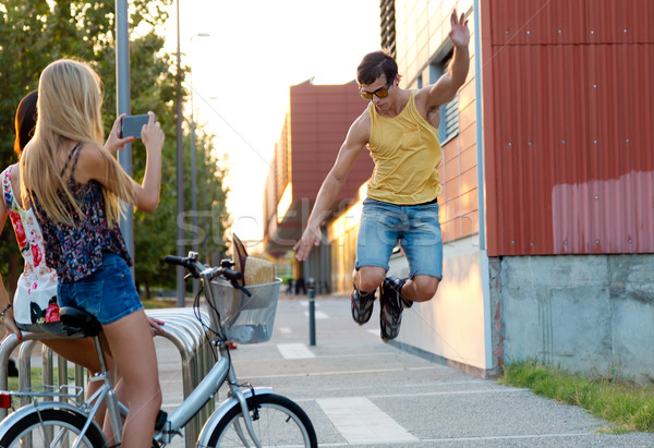 Young man with roller skates jumping and girls taking a photo. Stock photo © nenetus