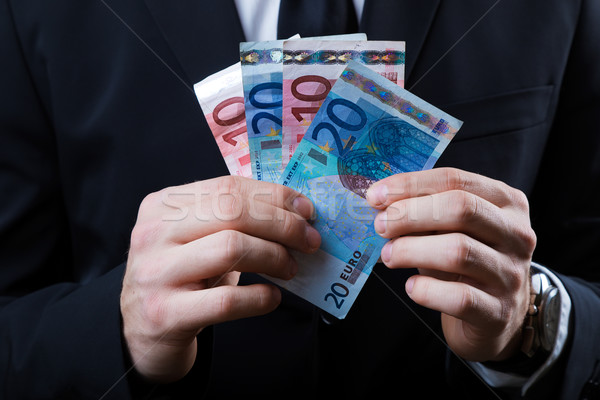 Stock photo: Young man in formalwear holding money.