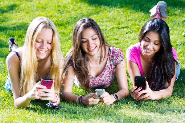 Stock photo: three girls chatting with their smartphones