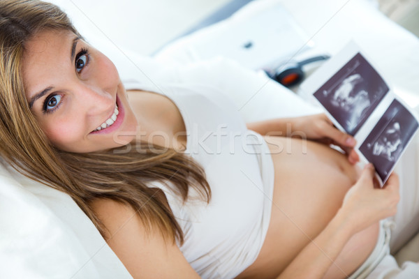 Stock photo: Pregnant woman looking at ultrasound scan of baby