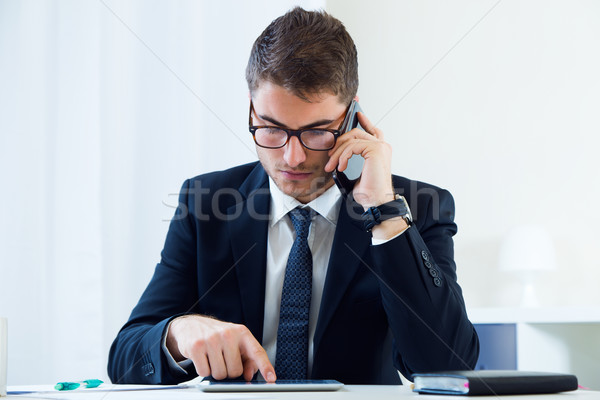 Young handsome man working in his office with mobile phone. Stock photo © nenetus