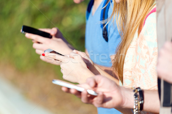 A group of students having fun with smartphones after class. Stock photo © nenetus