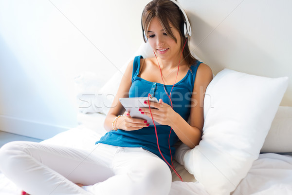 Beautiful girl listening to music with tablet on sofa at home. Stock photo © nenetus