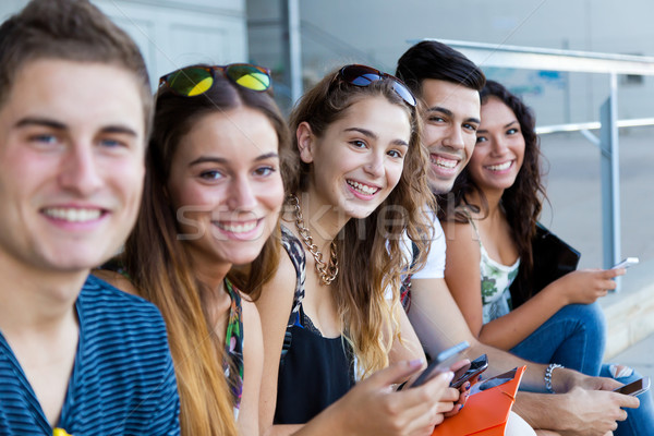 A group of students having fun with smartphones after class. Stock photo © nenetus