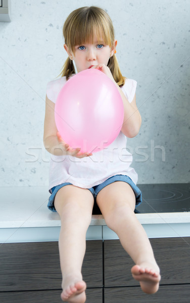Cute little  girl inflating a pink balloon in the kitchen Stock photo © nenetus