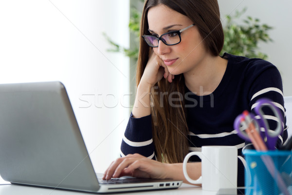 Confident young woman working in her office with laptop. Stock photo © nenetus