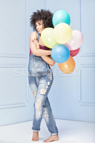 Stock photo: Happy young girl with afro holding balloons.