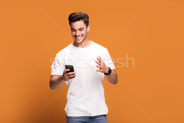 улыбаясь красивый мужчина мобильного телефона желтый счастливым Сток-фото © NeonShot