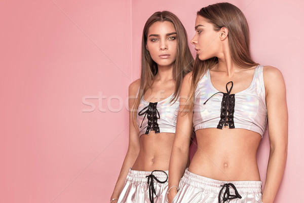 Fashionable twins sisters posing on pink background. Stock photo © NeonShot