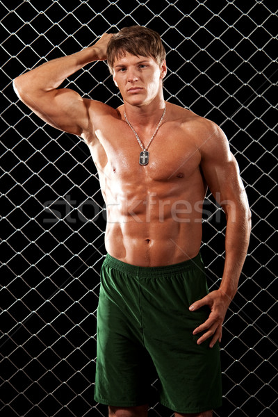 Male bodybuilder posing in front of chain link. Stock photo © nickp37