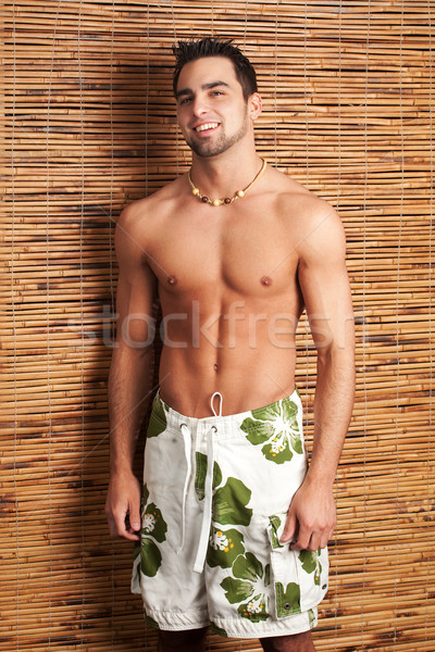Stock photo:  Attractive young man in boardshorts. Studio shot.