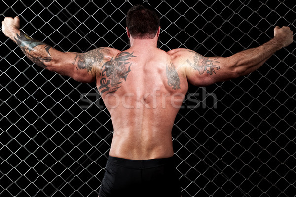 Bodybuilder posing in front of chain link. Stock photo © nickp37