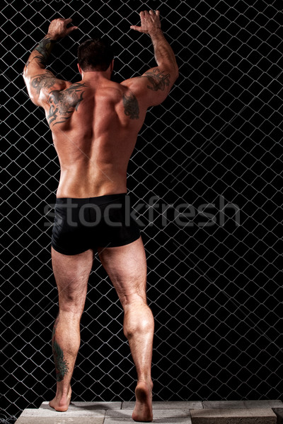 Bodybuilder posing in front of chain link. Stock photo © nickp37