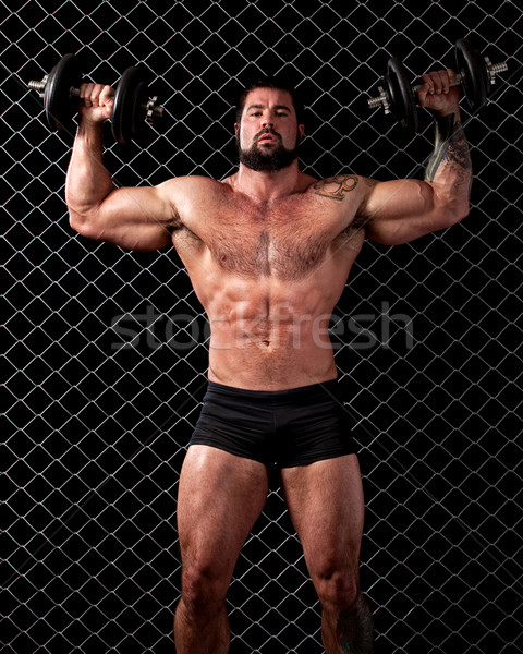 Stock photo: Bodybuilder posing in front of chain link.