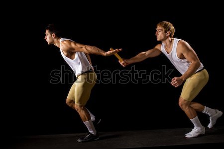 Relay racers passing the baton. Studio shot over black. Stock photo © nickp37