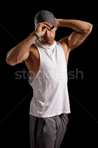 Muscular man putting on a baseball cap. Studio shot over black. Stock photo © nickp37