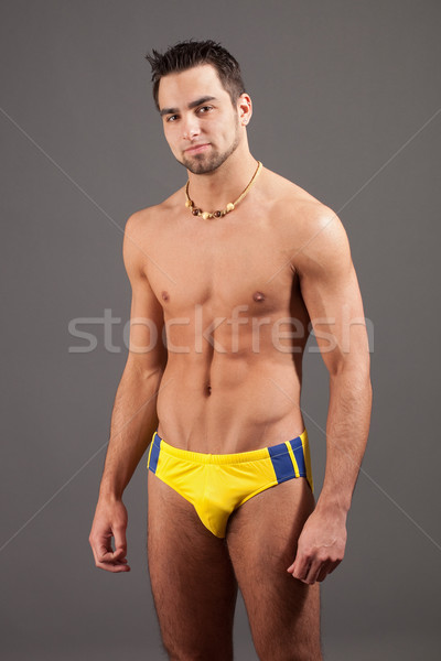 Attractive young man in swimsuit. Studio shot over grey. Stock photo © nickp37