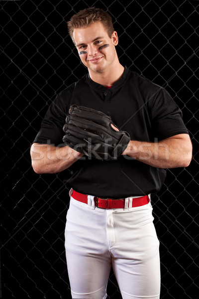 Stock photo: Young adult baseball player. Studio shot over black.