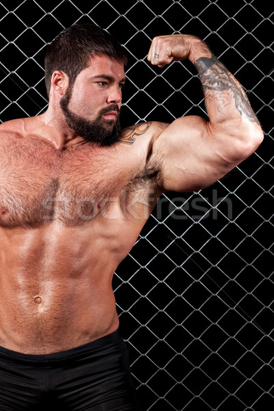 Bodybuilder posing in front of chain link. Stock photo © nickp37