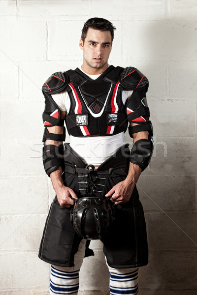 Stock photo: Ice hockey player in front of concrete block wall.