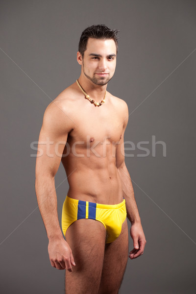 Attractive young man in swimsuit. Studio shot over grey. Stock photo © nickp37