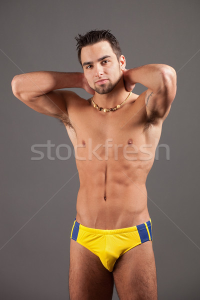 Attractive young man in swimsuit. Studio shot over grey. Stock photo © nickp37