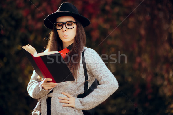 Surprised Student with Fedora, Glasses and Backpack Reading a Book Stock photo © NicoletaIonescu