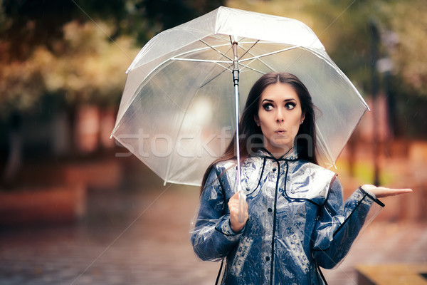 Stock photo: Woman with Transparent Raincoat and Umbrella Checking for Rain