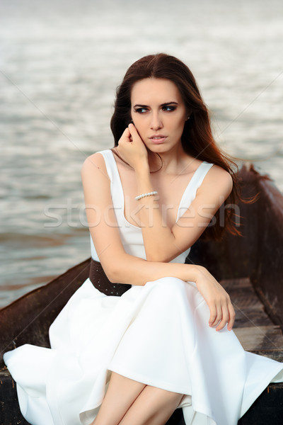 Sad Woman in White Dress Sitting in an Old Boat Stock photo © NicoletaIonescu