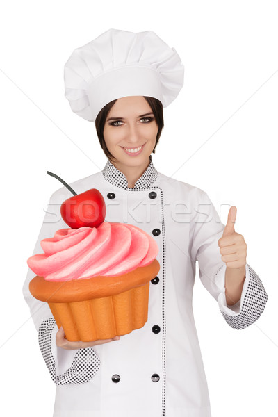 Woman Pastry Chef Holding Huge Cupcake Giving Thumbs up Sign Stock photo © NicoletaIonescu