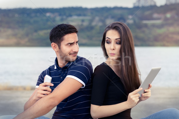 Secretive Couple with Tablet and Smartphone Stock photo © NicoletaIonescu