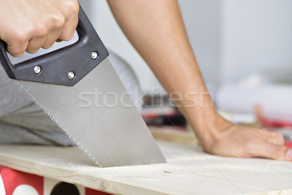 young man sawing a wooden board with a handsaw Stock photo © nito