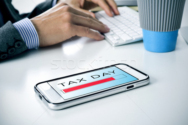 Stock photo: text tax day in a smartphone at the office