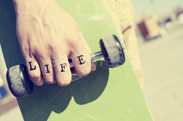 young man with the word life tattooed in his hand with a skatebo Stock photo © nito