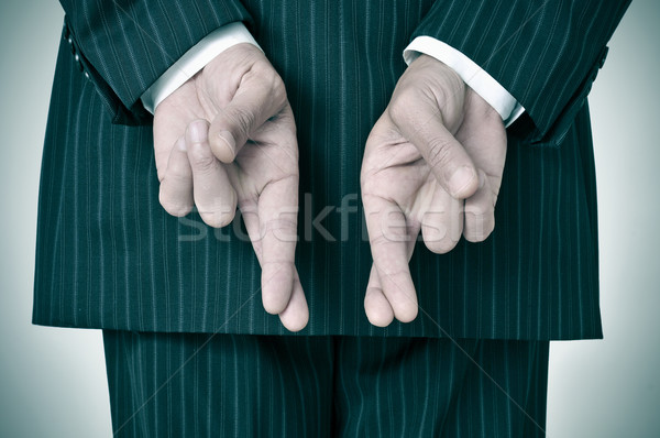 Stock photo: man wearing a suit crossing his fingers in his back