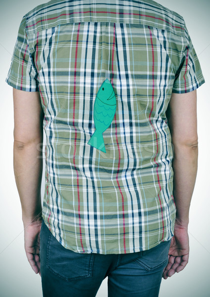 Stock photo: young man with a paper fish attached to his back