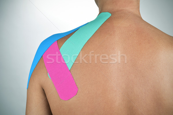 Stock photo: young man with some strips of elastic therapeutic tape in his ba