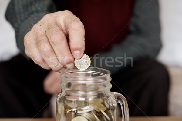 old man saving a one euro coin in a glass pot Stock photo © nito