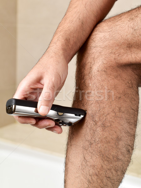 young man trimming his legs with an electric trimmer Stock photo © nito