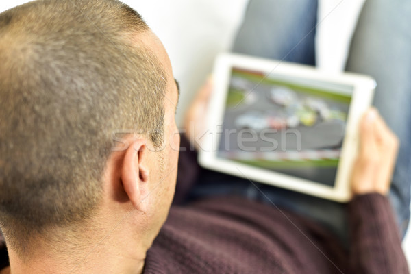 Młody człowiek oglądania samochodu wyścigu tabletka kanapie Zdjęcia stock © nito