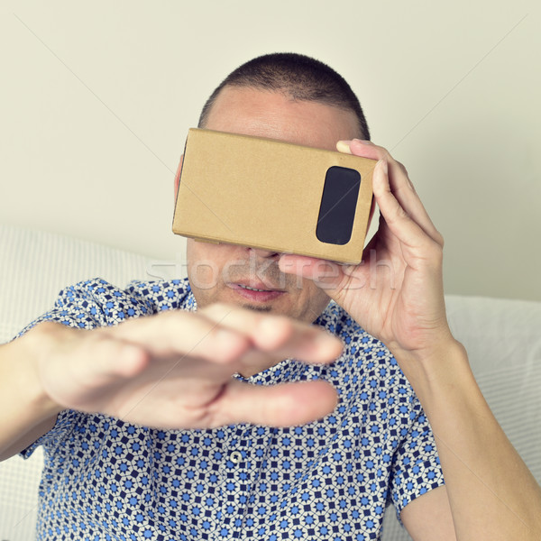 young man using cardboard virtual reality lenses Stock photo © nito