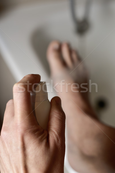 young man applying deodorant to his feet Stock photo © nito