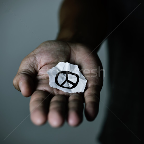 Stock photo: man with a peace symbol in a piece of paper