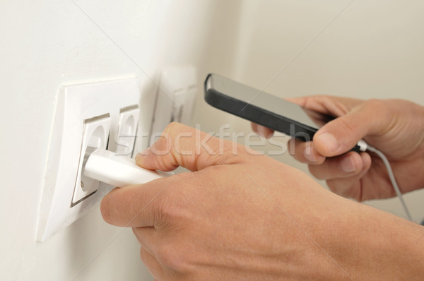 man plugging in the plug of his smpartphone in a socket Stock photo © nito