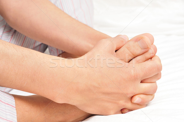 young man in pajamas grabbing his feet with his hands Stock photo © nito