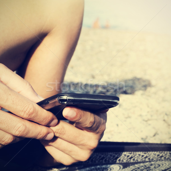 young man using a smartphone on the beach, filtered Stock photo © nito