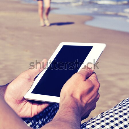 Férfi tabletta ekönyv tengerpart retro szűrő Stock fotó © nito