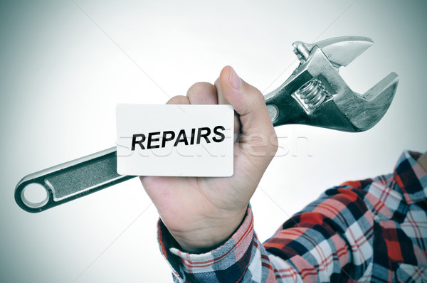 man with an adjustable wrench and a signboard with text repairs Stock photo © nito