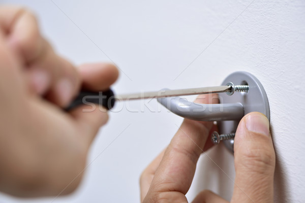 young man screwing a hook in the wall Stock photo © nito