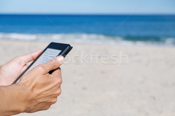 man reading in a tablet or e-reader on the beach Stock photo © nito